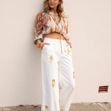 Adriana Embellished Pants - white wide-leg pant with high waist, pocket and embroidered gold sun embellishment