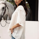 Atti Blouse is a delicate white blouse featuring short sleeves and lace detail.