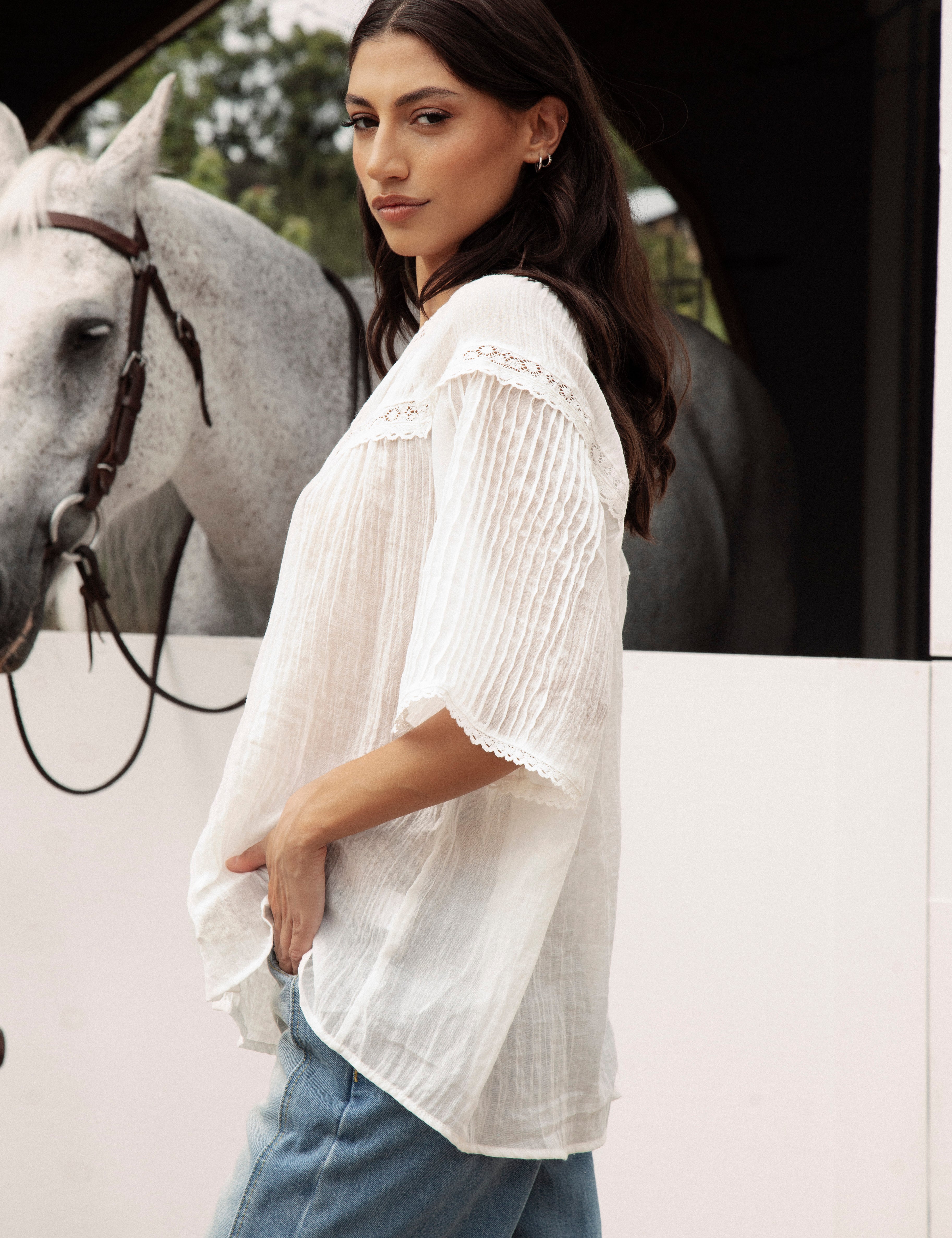 Atti Blouse is a delicate white blouse featuring short sleeves and lace detail.
