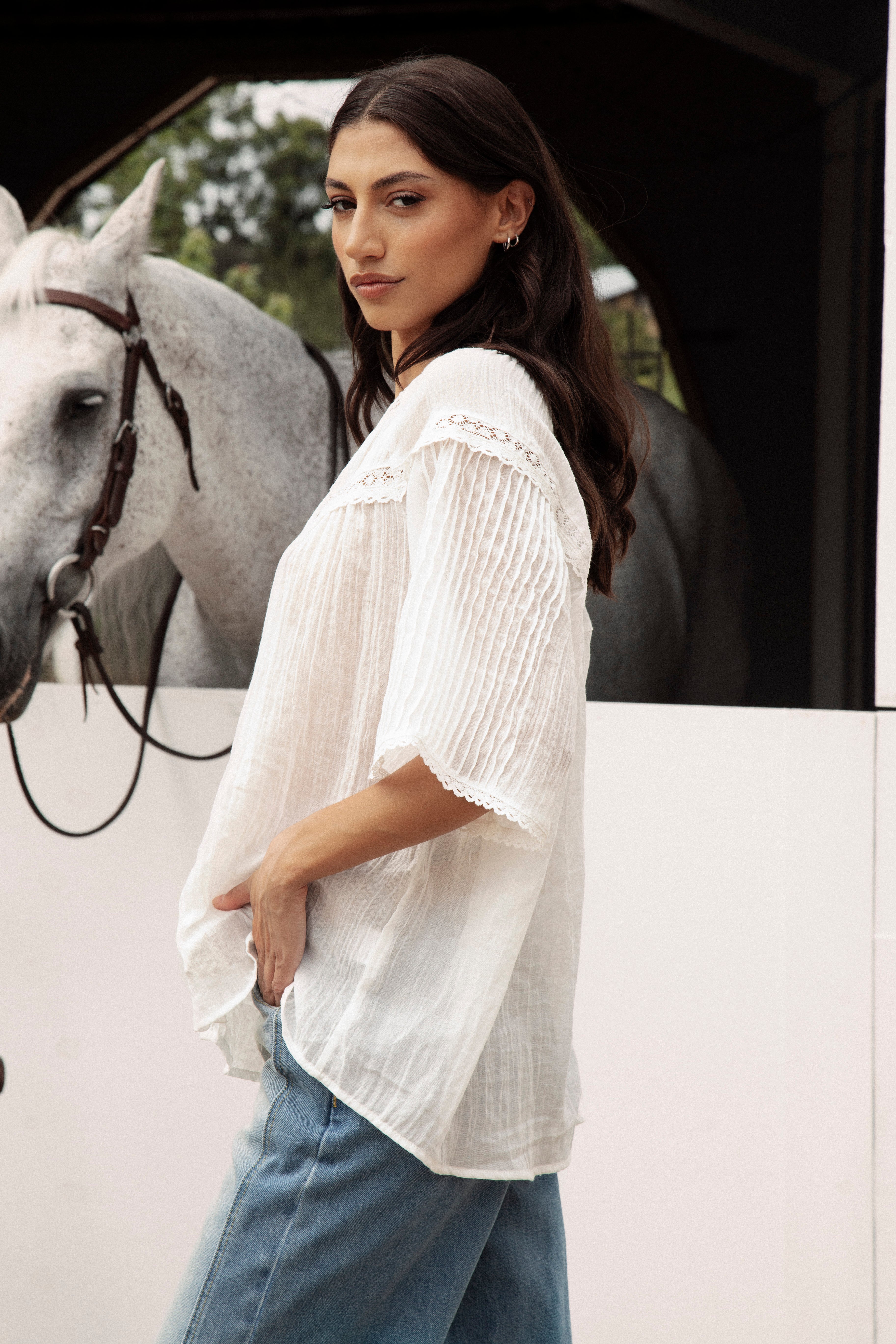 Atti Blouse is a delicate white blouse featuring short sleeves and lace detail.