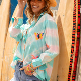 Cosmo Shirt Aquamarine is a light blue and white striped sheer button-up shirt with a colorful butterfly embroidered motif and contrasting stitching at cuffs. Worn with Fergie Denim Shorts, and a straw hat.