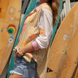 Cosmo Shirt Sandy - side view showcasing contrasting white sleeves with embroidered motifs in shades of yellow, orange and pink.