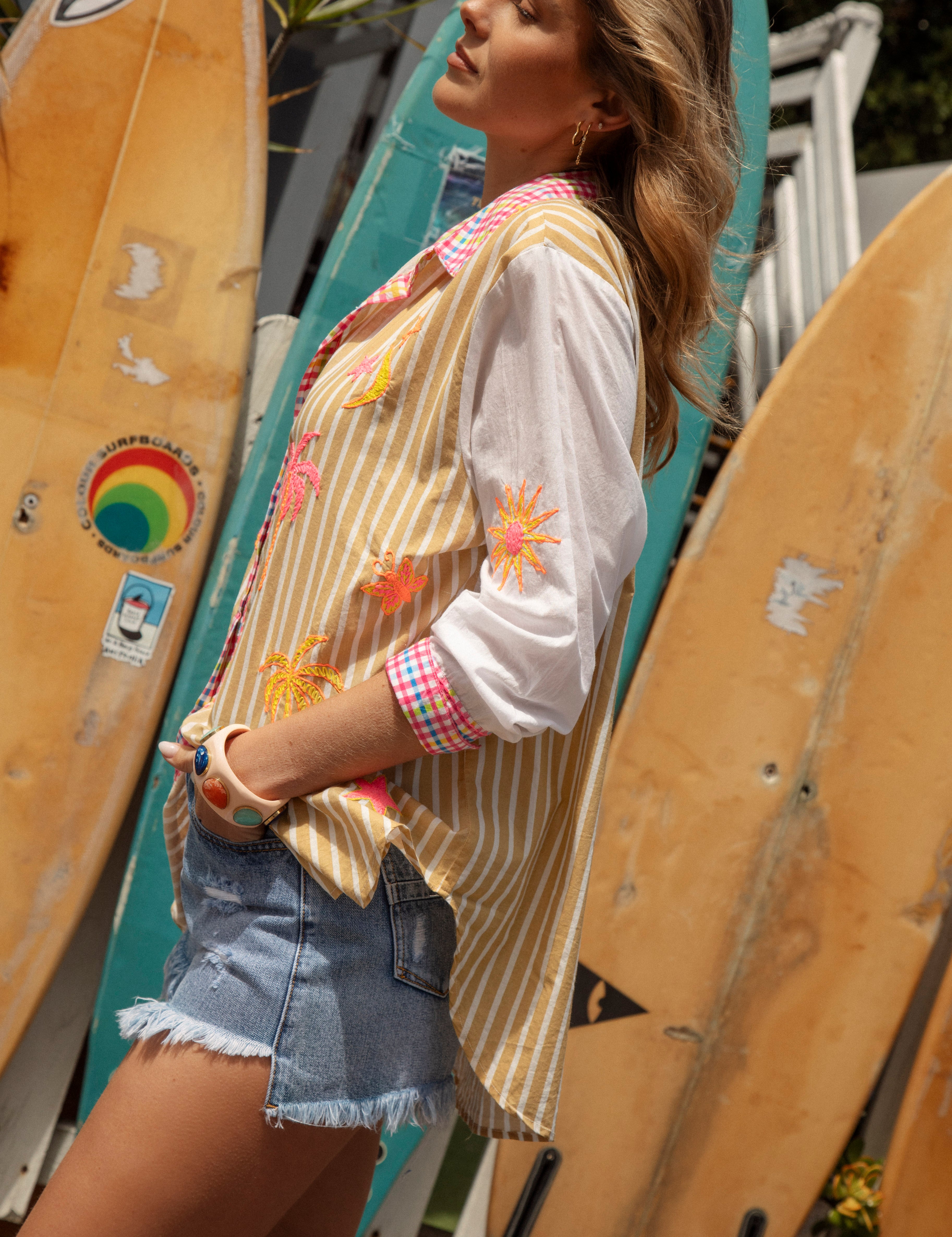 Cosmo Shirt Sandy - side view showcasing contrasting white sleeves with embroidered motifs in shades of yellow, orange and pink.