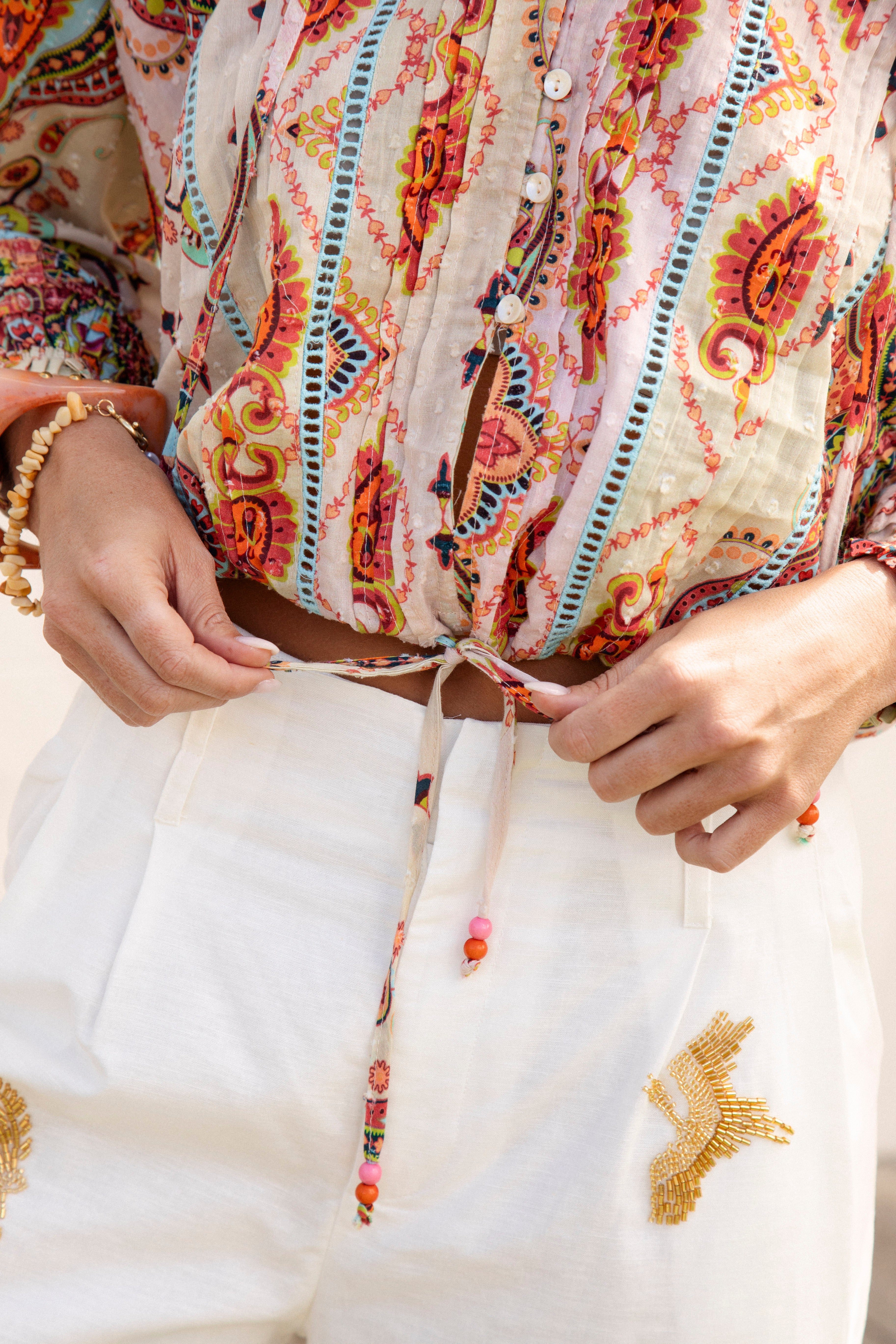 Delfi Blouse Rio - close up view of drawstring tie at waist, button down detail and paisley print