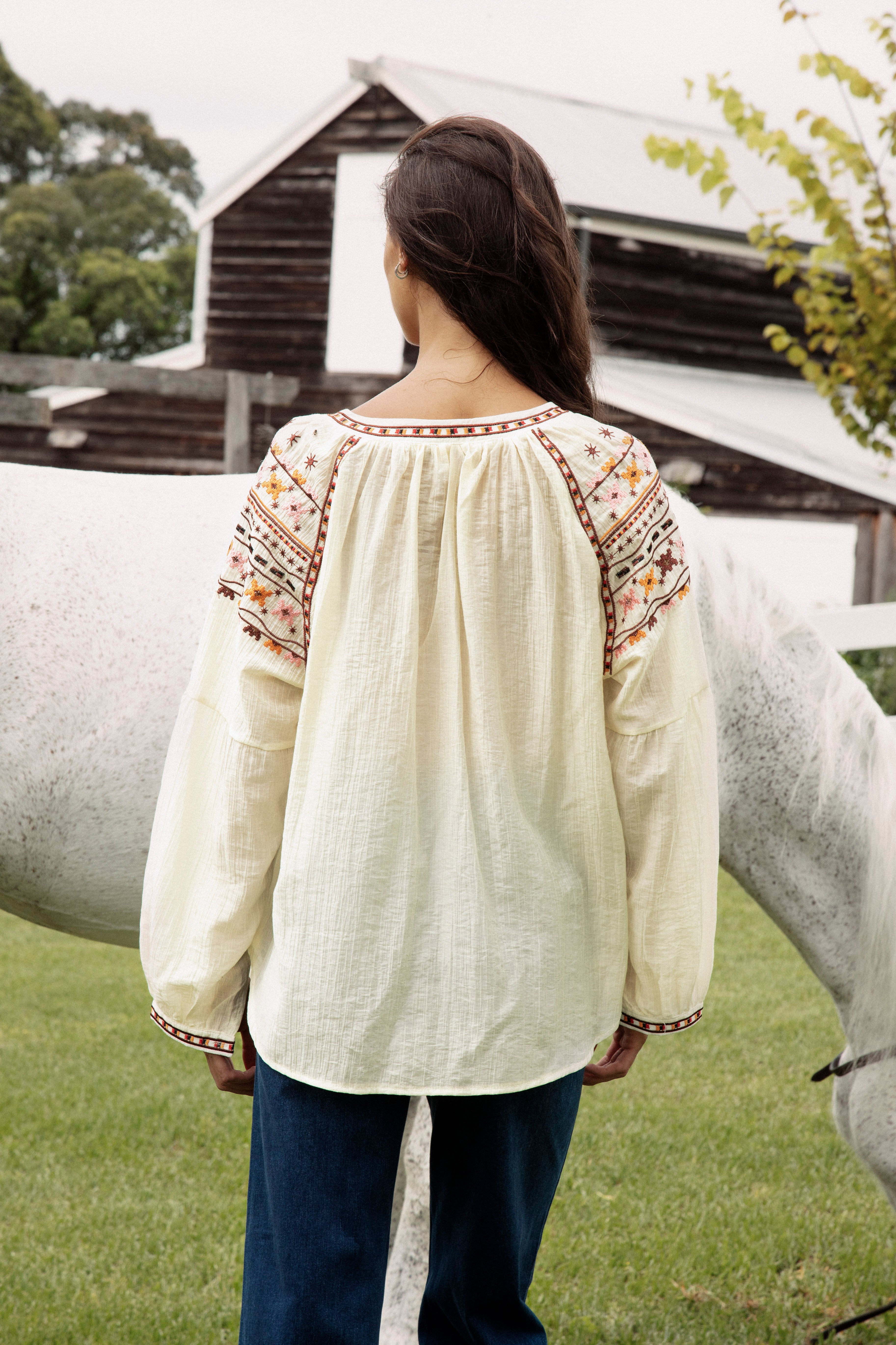 Eve Embroidered Blouse. Rear view showcasing oversized fit and delicate embroidered detail at sleeves, neckline and cuffs.