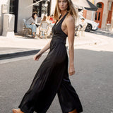 Gigi Jumpsuit Black - side view showcasing halter neckline and wide leg pants