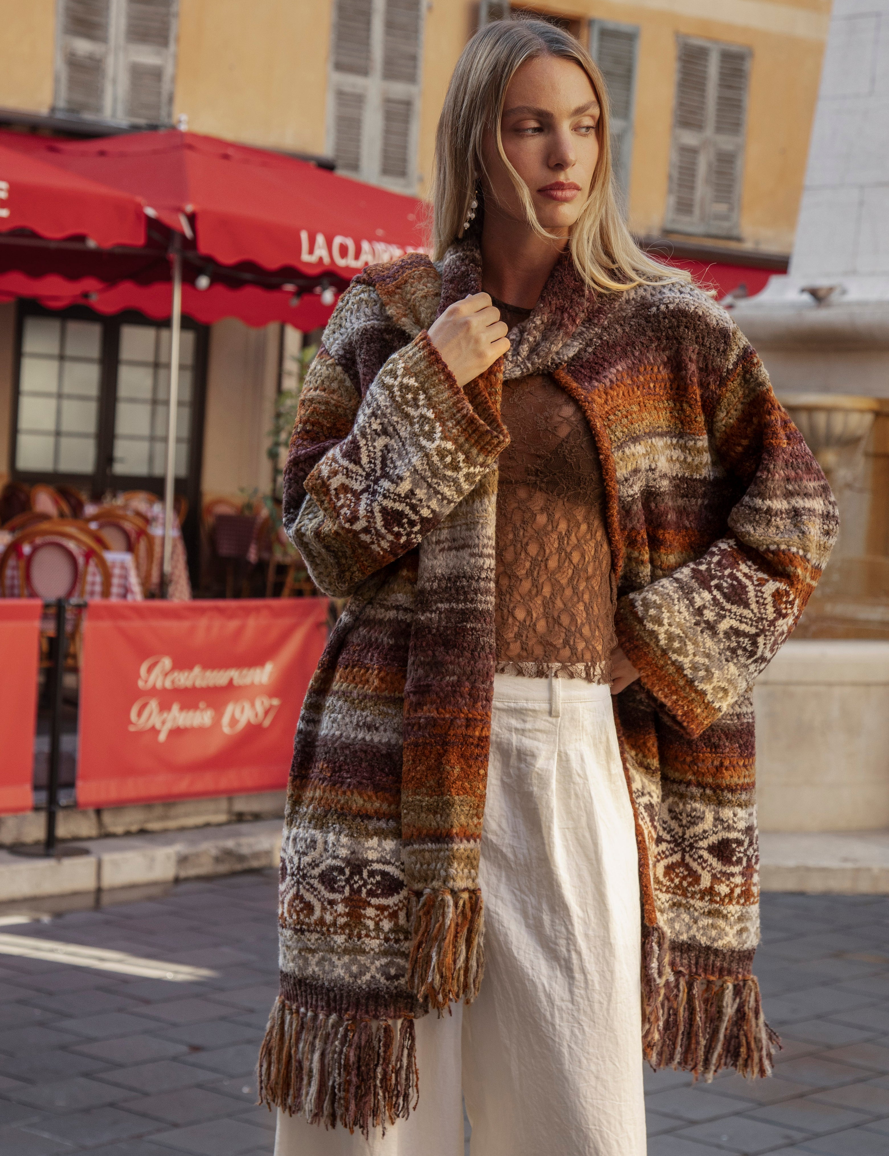 La Vie Cardigan is a chunky knit open-front cardigan with a multicolor pattern of brown, beige, orange, and black worn with Sol Pant - Pearl.