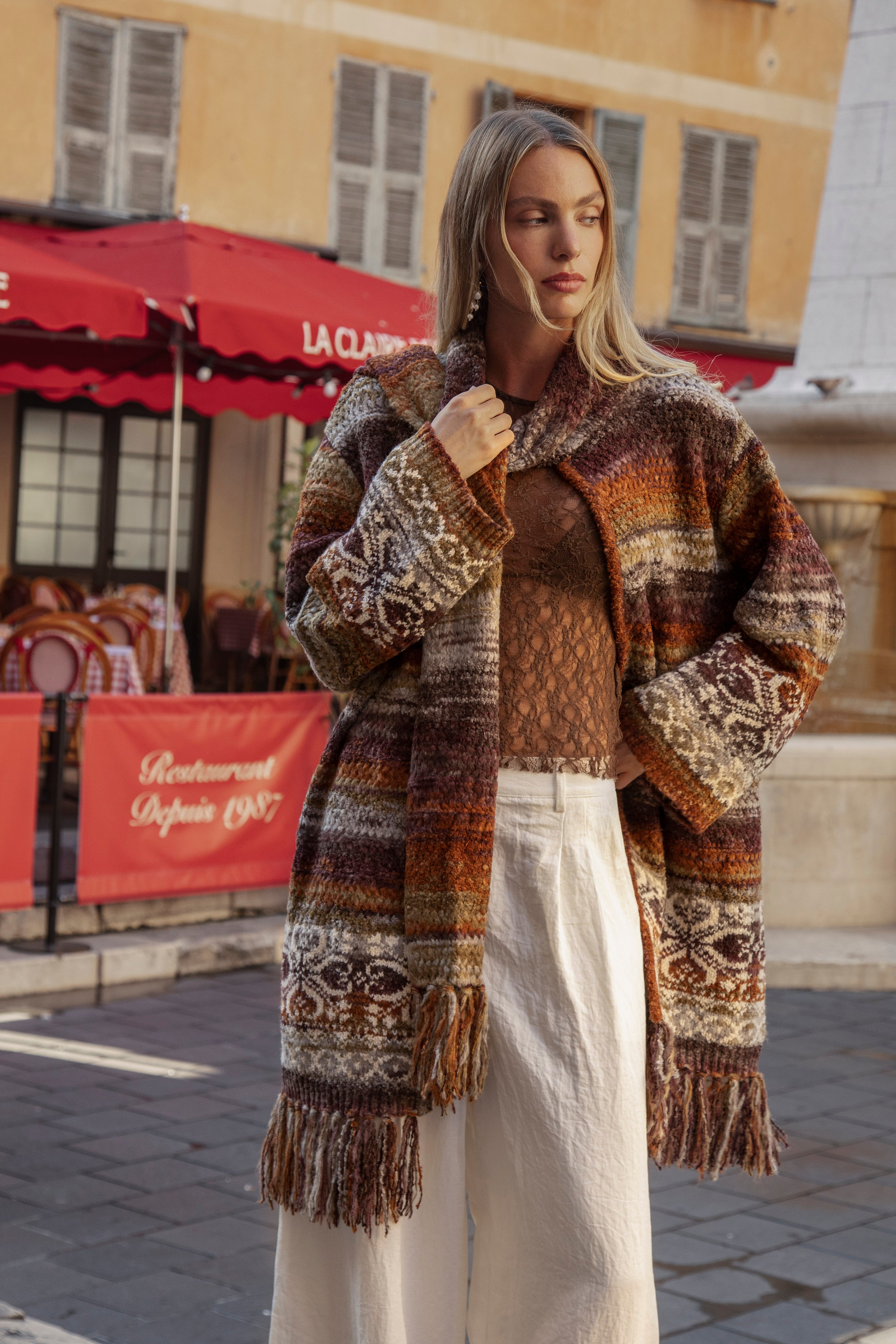 La Vie Cardigan is a chunky knit open-front cardigan with a multicolor pattern of brown, beige, orange, and black worn with Sol Pant - Pearl.