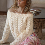 Seraphine Off Shoulder Knit Cream. A sweater in cream colourway featuring off the shoulder style and textured cable knit throughout.