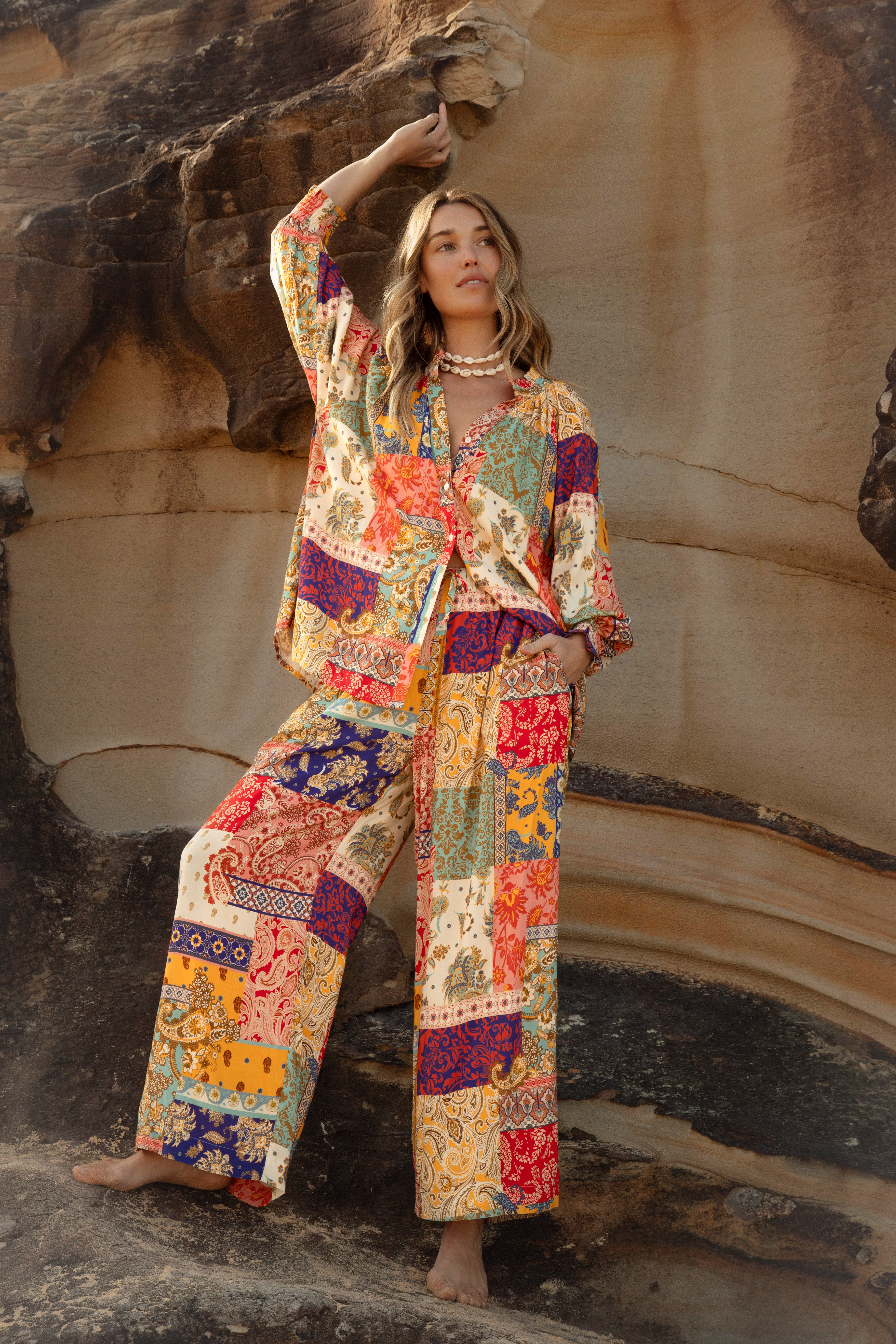 Sunseeker Blouse features patchwork pattern and boho style. Crafted from 100% rayon with buttons down the front, long sleeve and collar detail.