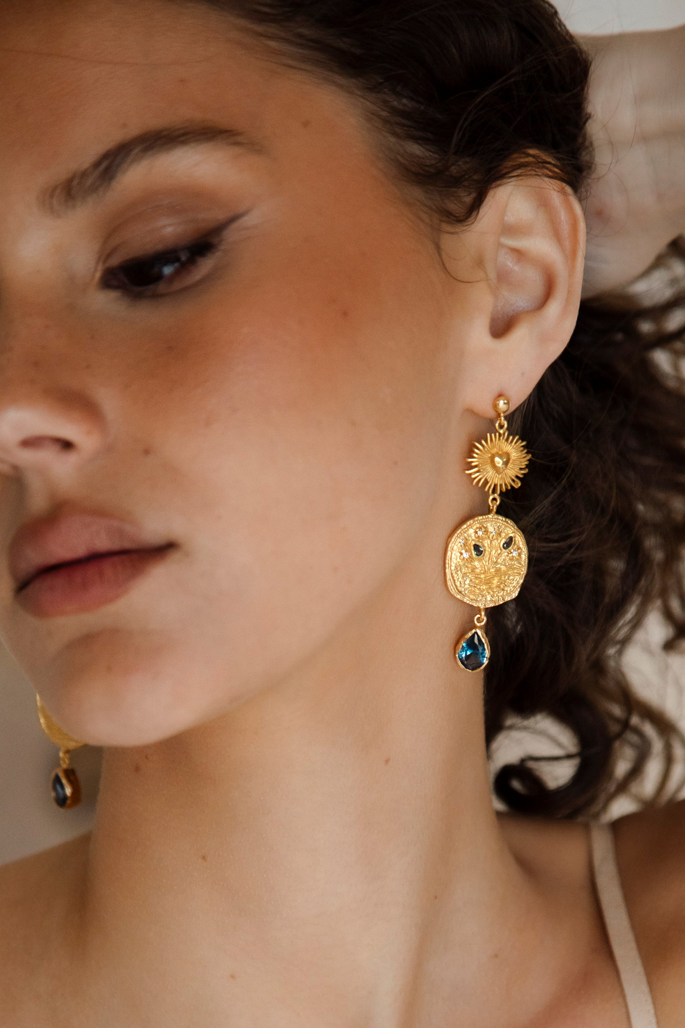 The Collectors Trove Earrings - gold drop earring featuring tiered drop of golden discs and sapphire blue gems