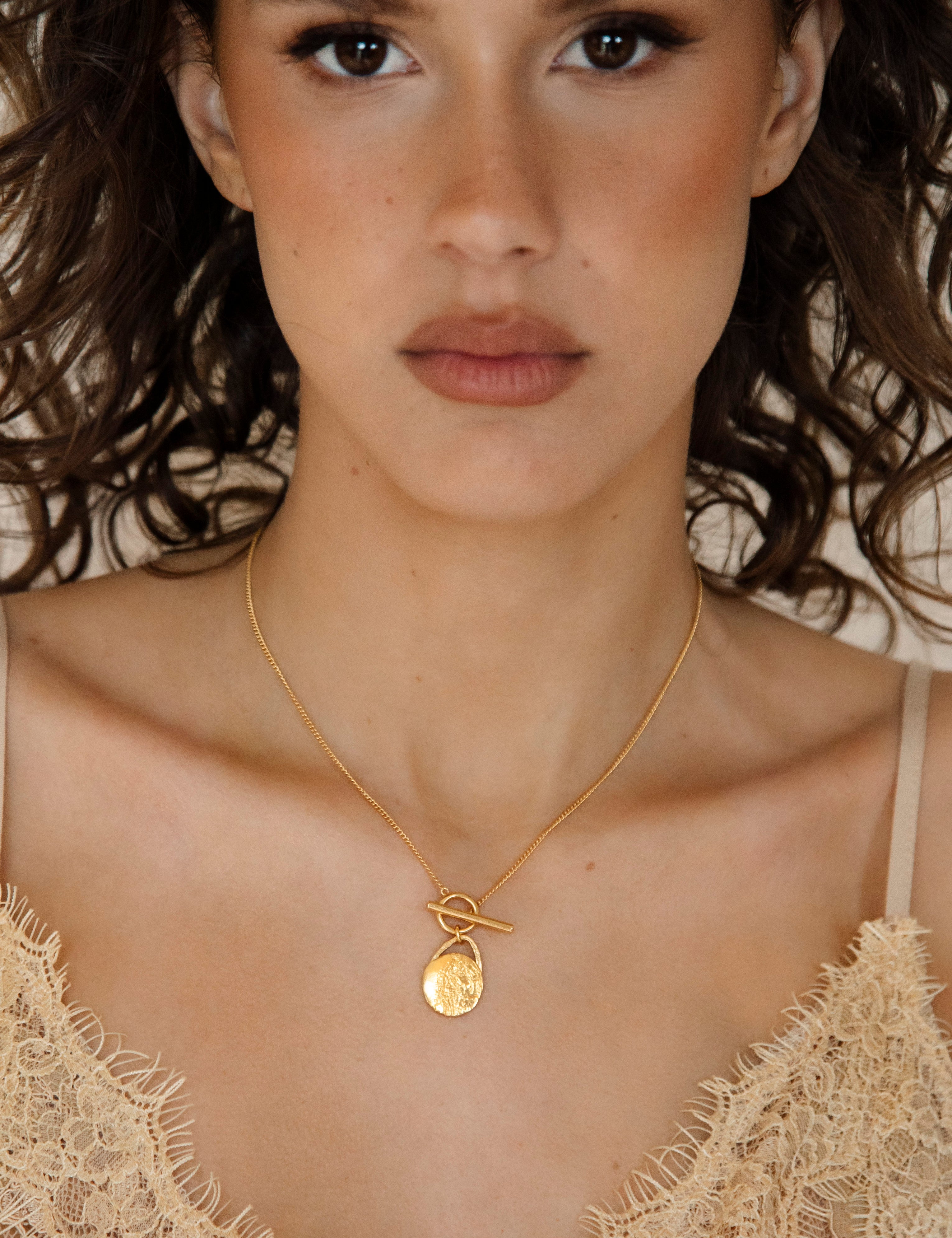 The Tell-Tale Heart Necklace features textured golden disc pendant on gold chain