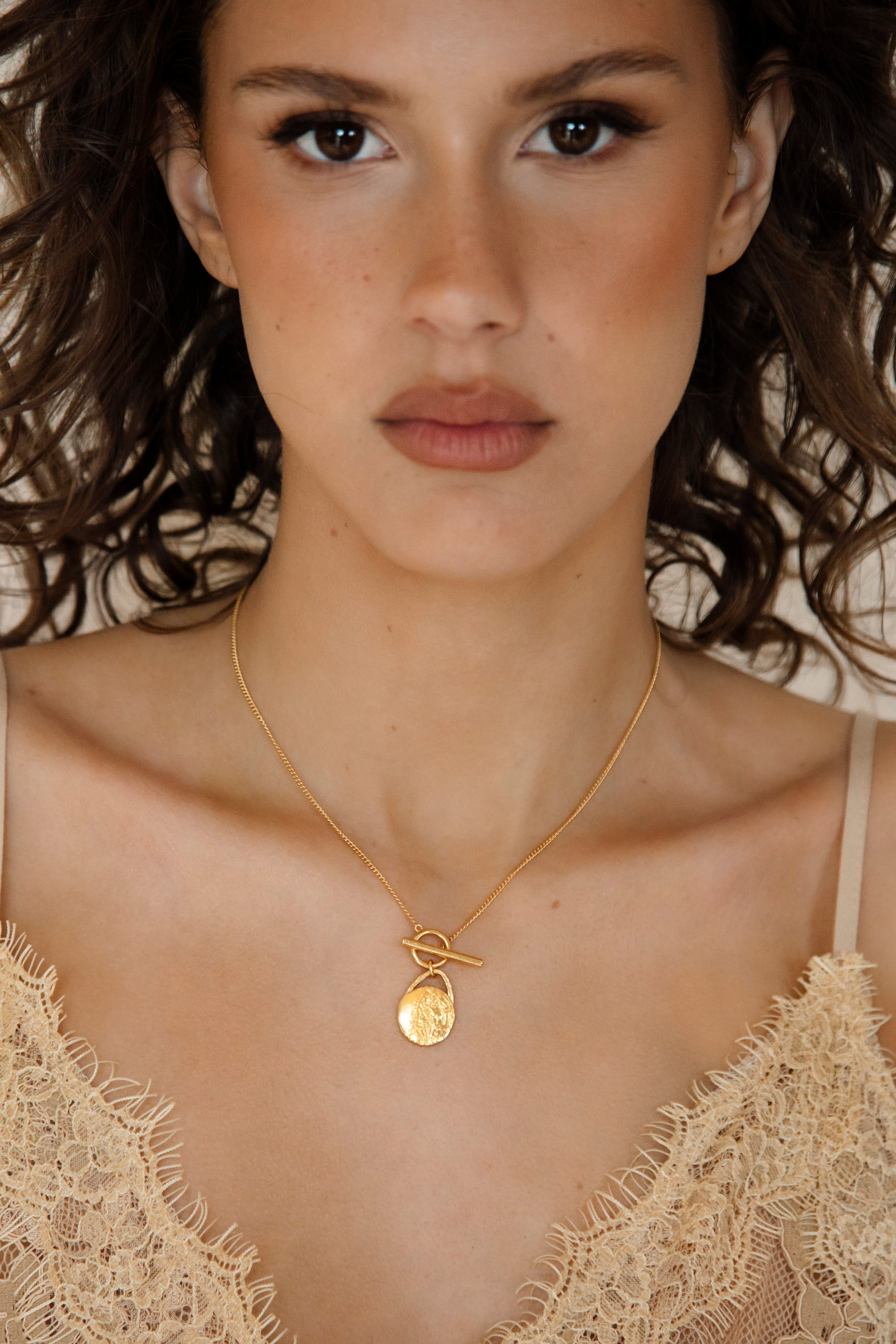 The Tell-Tale Heart Necklace features textured golden disc pendant on gold chain