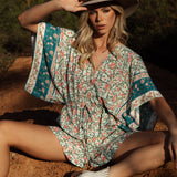 Vida Playsuit featuring floral pattern in shades of pink and green on aqua background