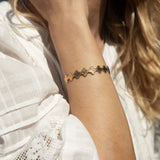 Close-up of a person wearing a gold bracelet on a blurred background