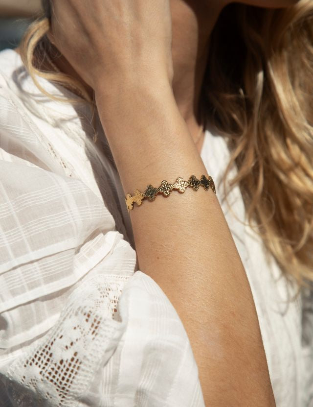 Close-up of a person wearing a gold bracelet on a blurred background