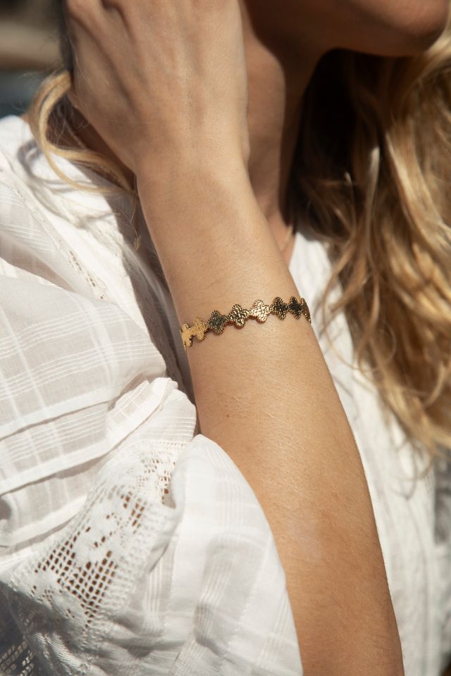 Close-up of a person wearing a gold bracelet on a blurred background